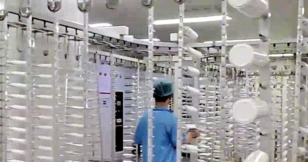 Spraying line with bottles hanging on racks in a clean room
